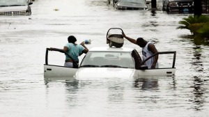 A man puts his baby on top of his car as he and a woman abandon their car after it started to float in ...